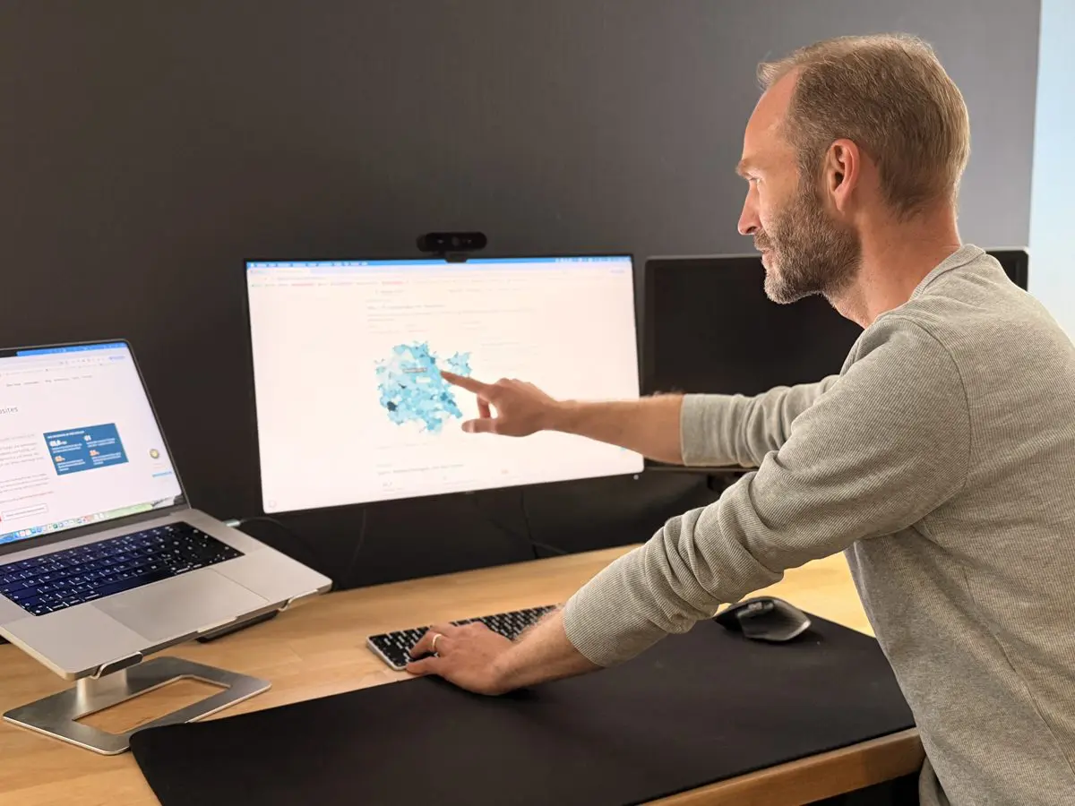 Stephan Zabel – SEO, Google Ads und GEO aus Nürnberg Stephan Zabel, SEO-, SEA- und GEO-Freelancer aus Nürnberg, erklärt an seinem Arbeitsplatz die Karte des Digital-Atlas Mittelfranken